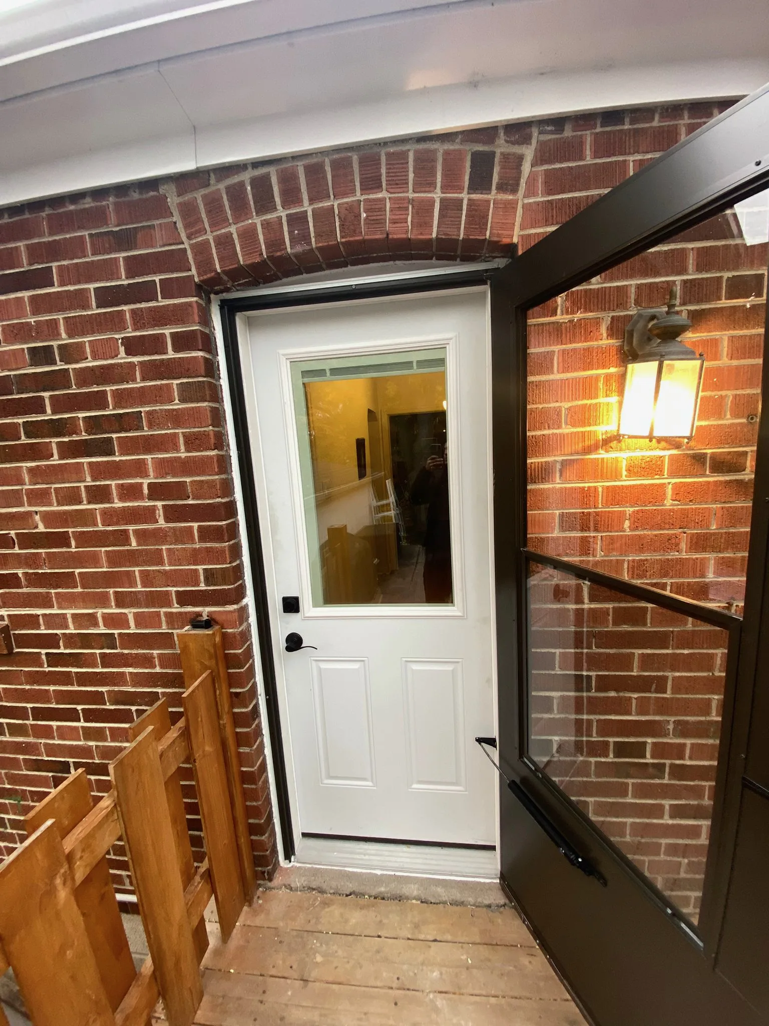 White residential entry door and open storm door in a brick wall