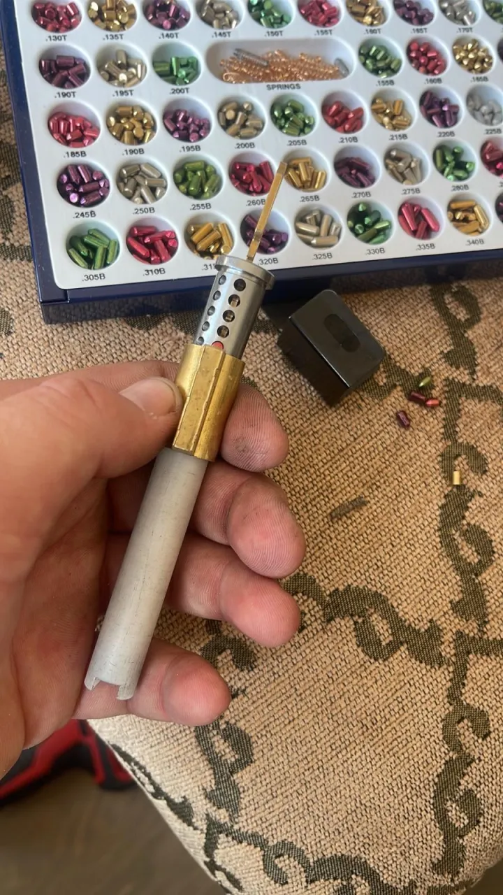 Lock cylinder being rekeyed beside a colour-coded pin kit